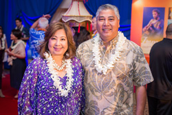 Two people stand together and smile while attending an indoor event.