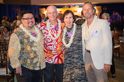 A group of four people smile together while attending an event.