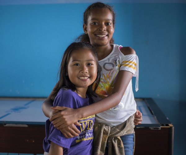 Two young girls smiling and hugging