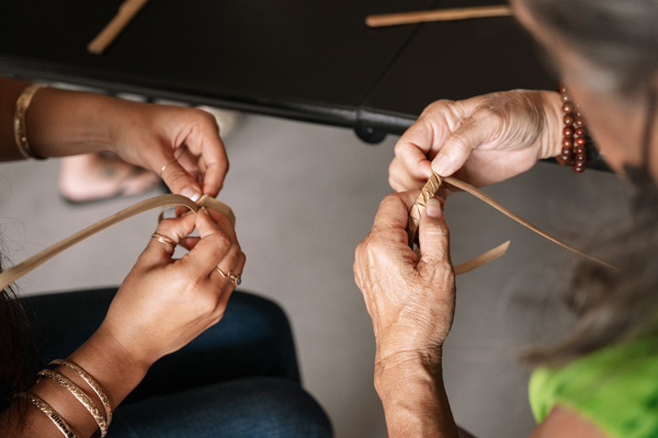 Two sets of hands each creating a bracelet by hand