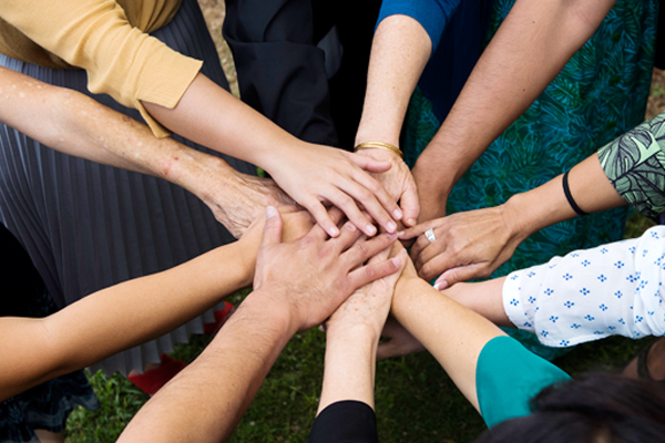 A group puts their hands into the center of a circle.